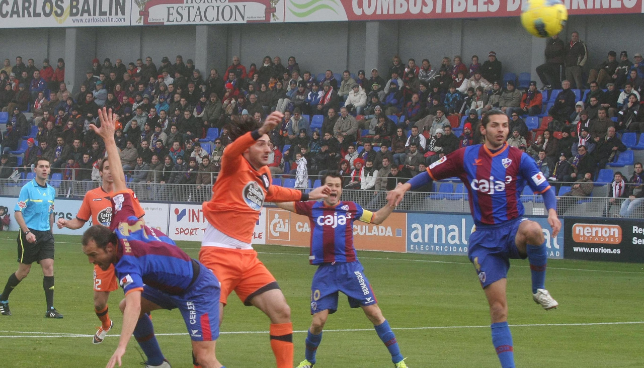 Colotto acaba de cabecear por encima de Luis Helguera el primer tanto del Deportivo en su victoria ante el Huesca en El Alcoraz el 15 de enero de 2012