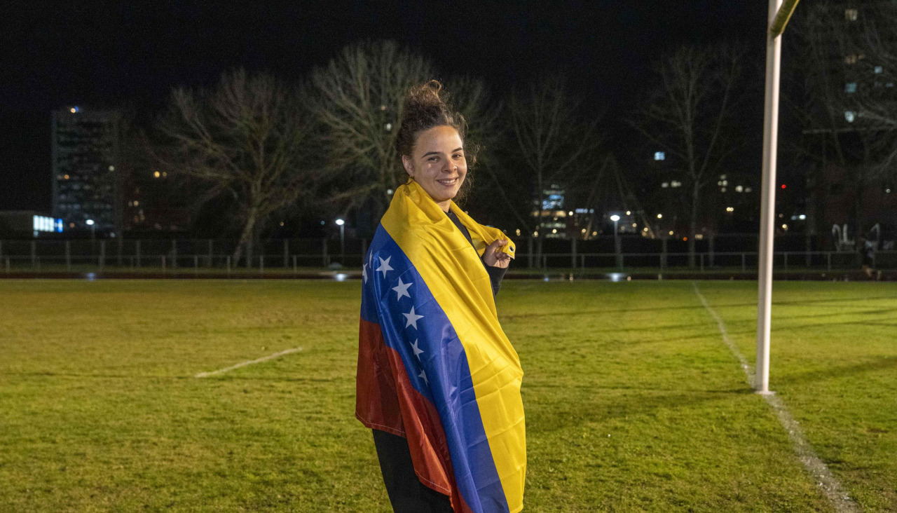 Mariana Romero, jugadora del CRAT, posa con la bandera de Venezuela en el campo del Campus de Elviña