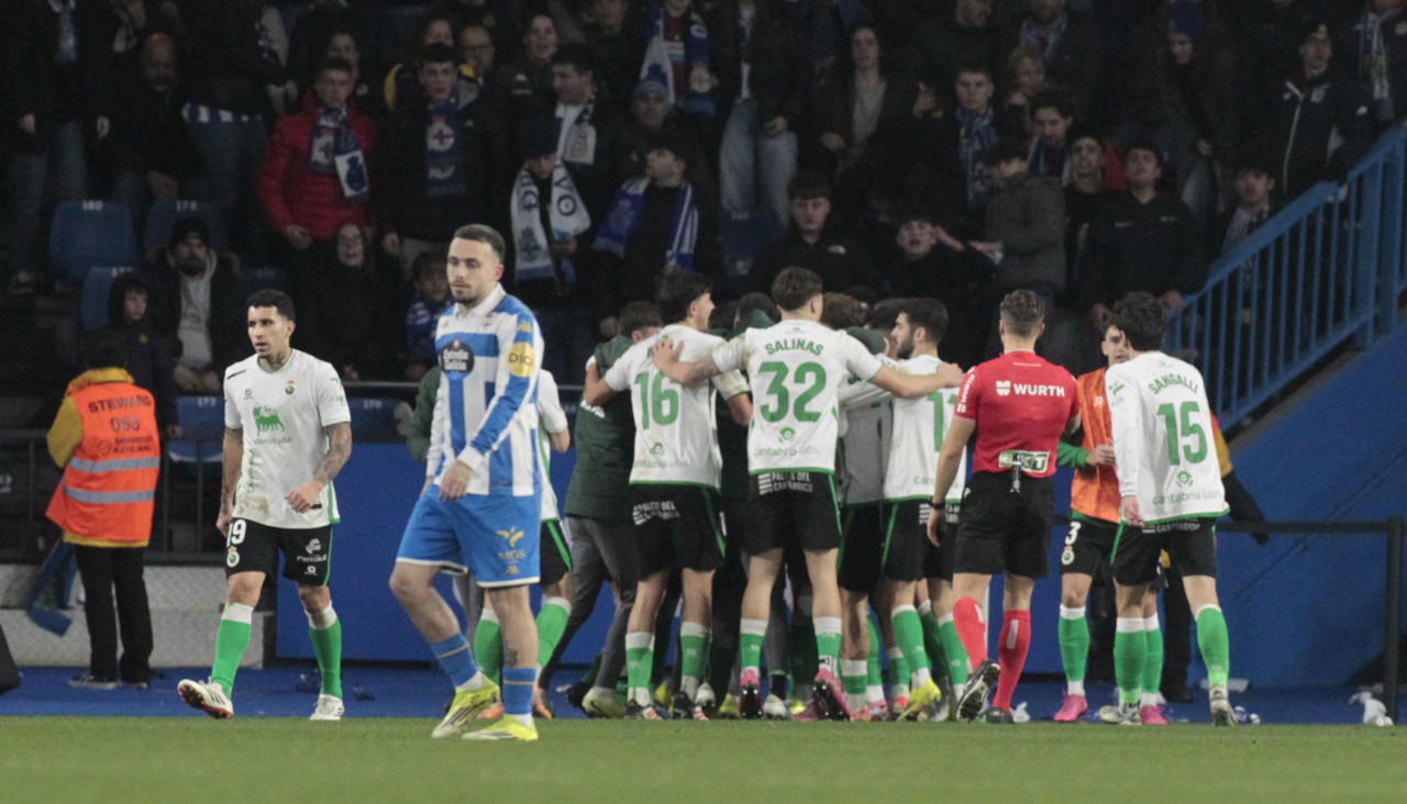 Mella lamenta el gol del Racing mientras los futbolistas del equipo cántabro celebran sobre el césped de Riazor