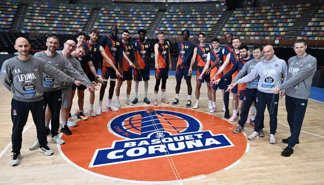 Plantilla y cuerpo técnico del Básquet Coruña posan para DXT Campeón junto al escudo del equipo en el Coliseum