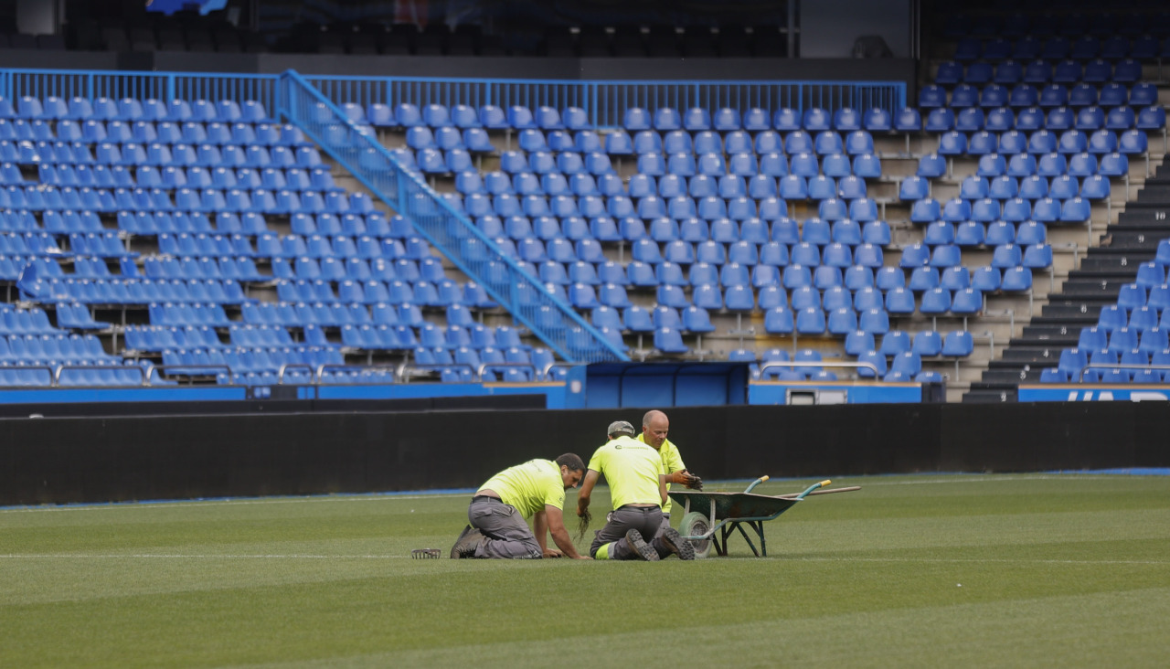 Jardineros tratando de arreglar los desperfectos en el césped de Riazor