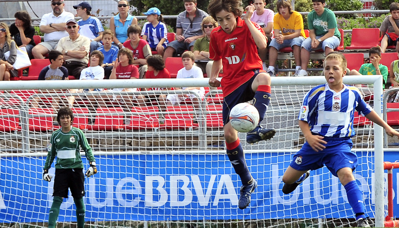 Angeliño presiona a un jugador de Osasuna en el XVI Torneo Nacional Blue BBVA Alevín de Fútbol 7 de 2009 en A Torre, con Jano López al fondo