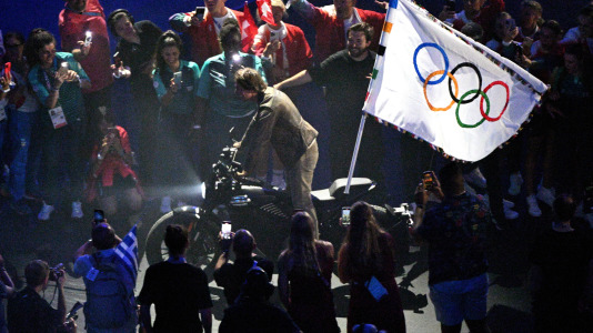 El actor estadounidense Tom Cruise porta la bandera olímpica